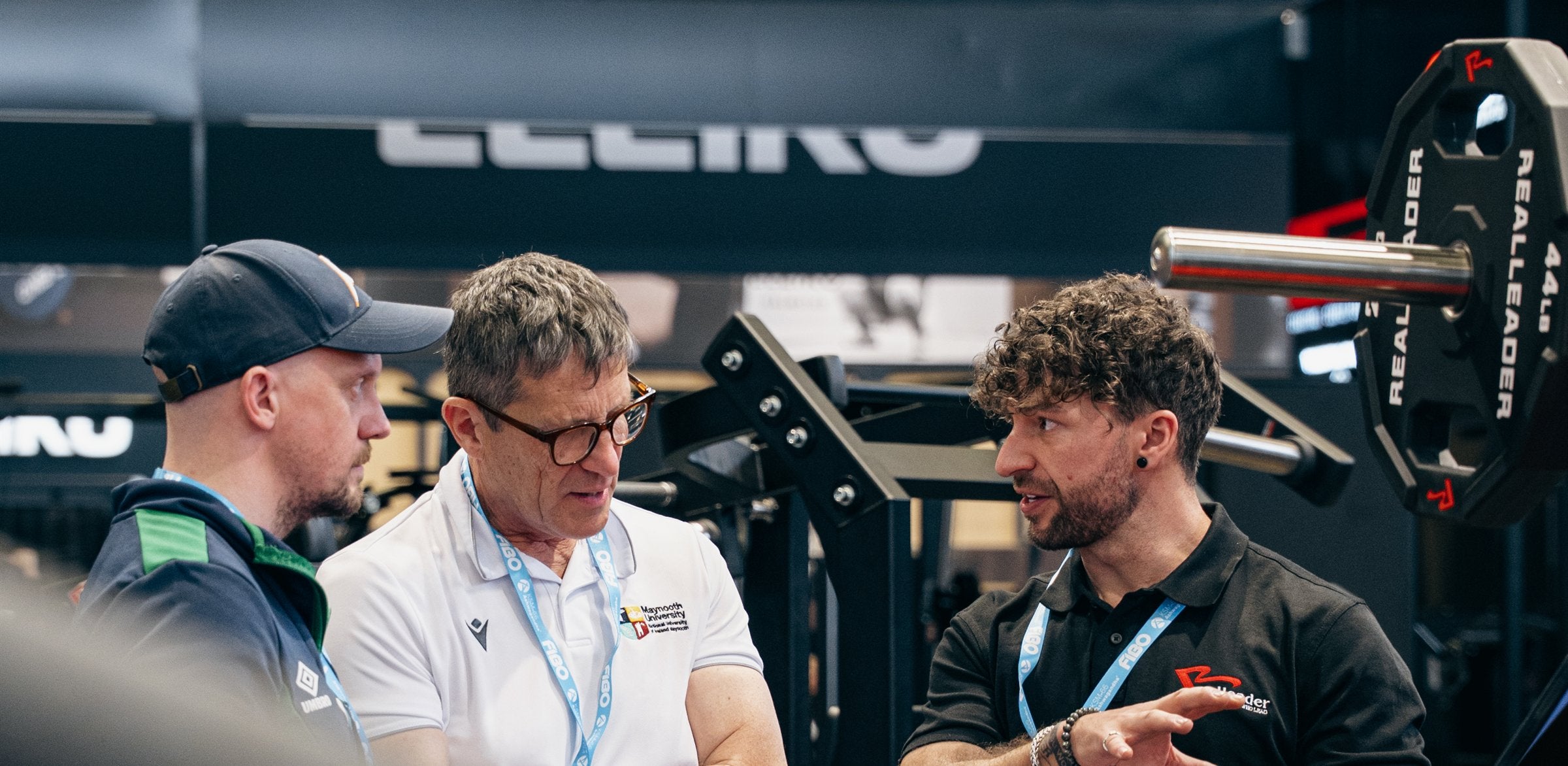 Realleader team discussing strength equipment in a showroom